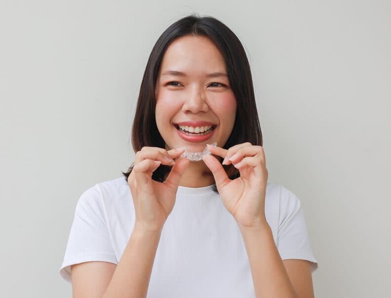 A woman holding a clear aligner